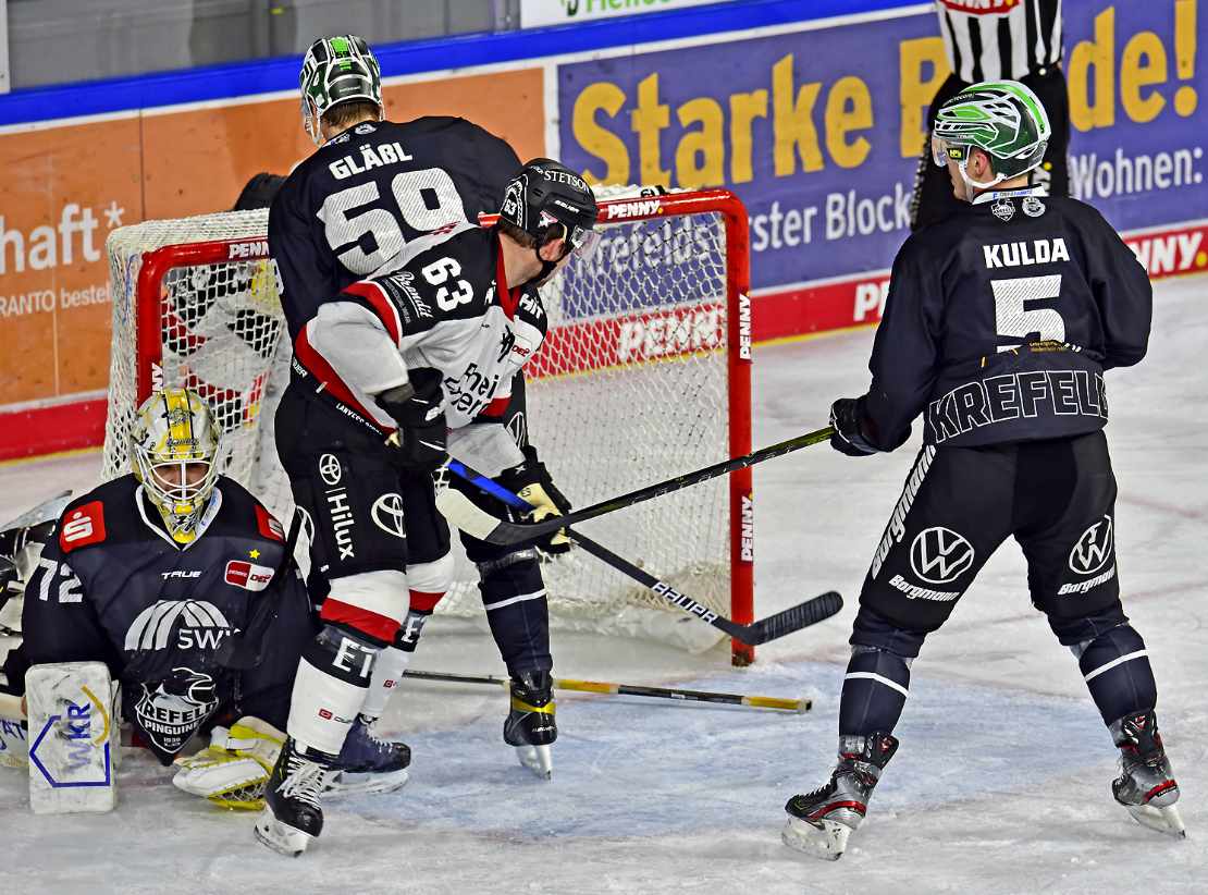 Mehrere Eishockeyspieler kämpfen vor dem Tor um den Puck